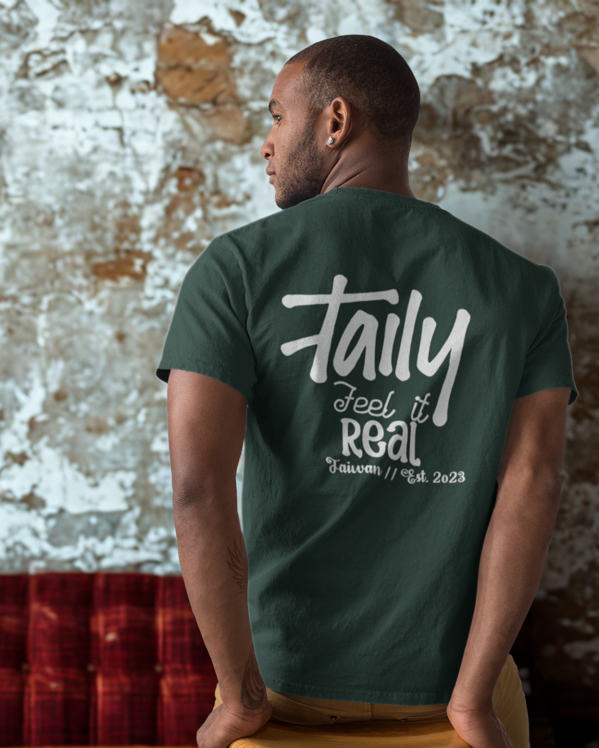 Model wearing Taily Feel It Real boxy tee in forest green with bold lettering on back.