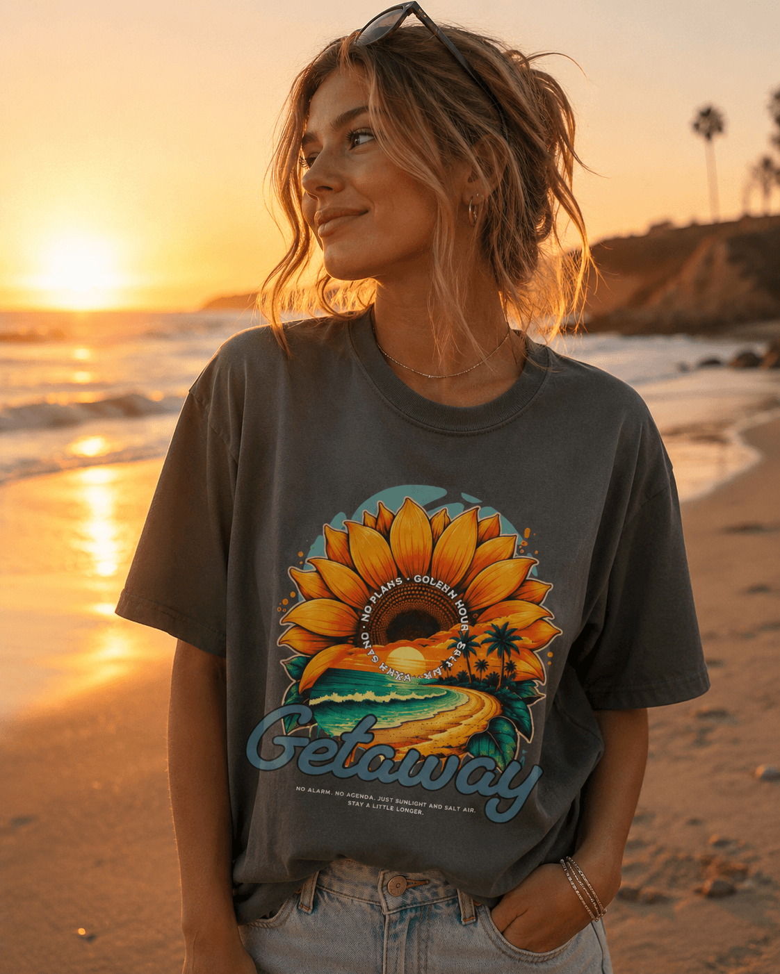 Model wearing Getaway Sunflower Beach Tee – Pepper on the beach at sunset, featuring a sunflower design.