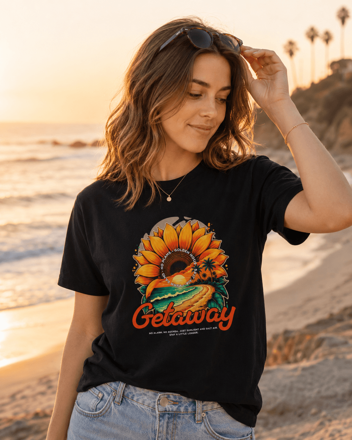 Getaway Sunflower Beach Tee – Black worn by a woman on the beach at sunset, featuring a vibrant sunflower graphic.