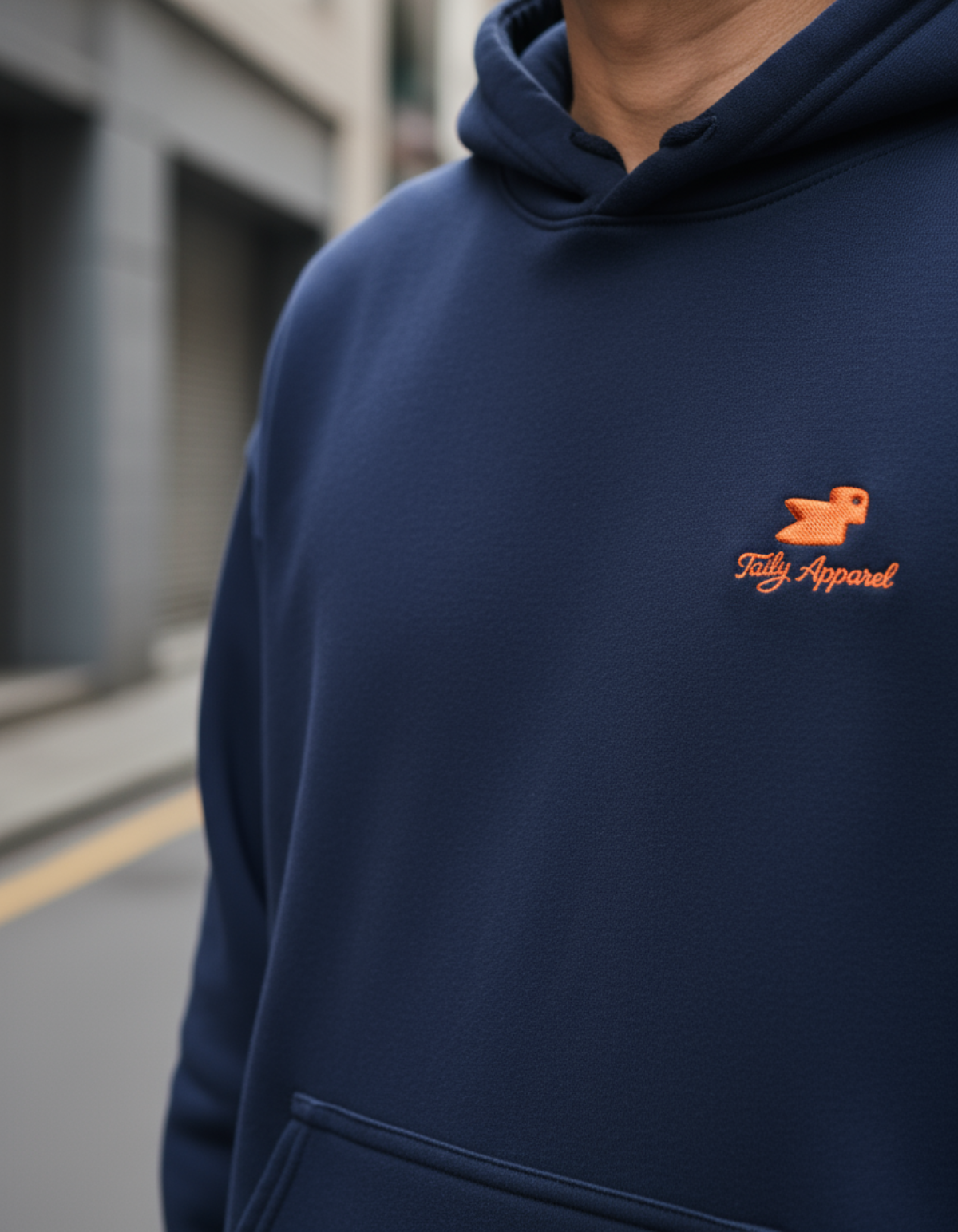 Taily Bird embroidered hoodie in navy with orange bird logo, showcasing minimal streetwear style.