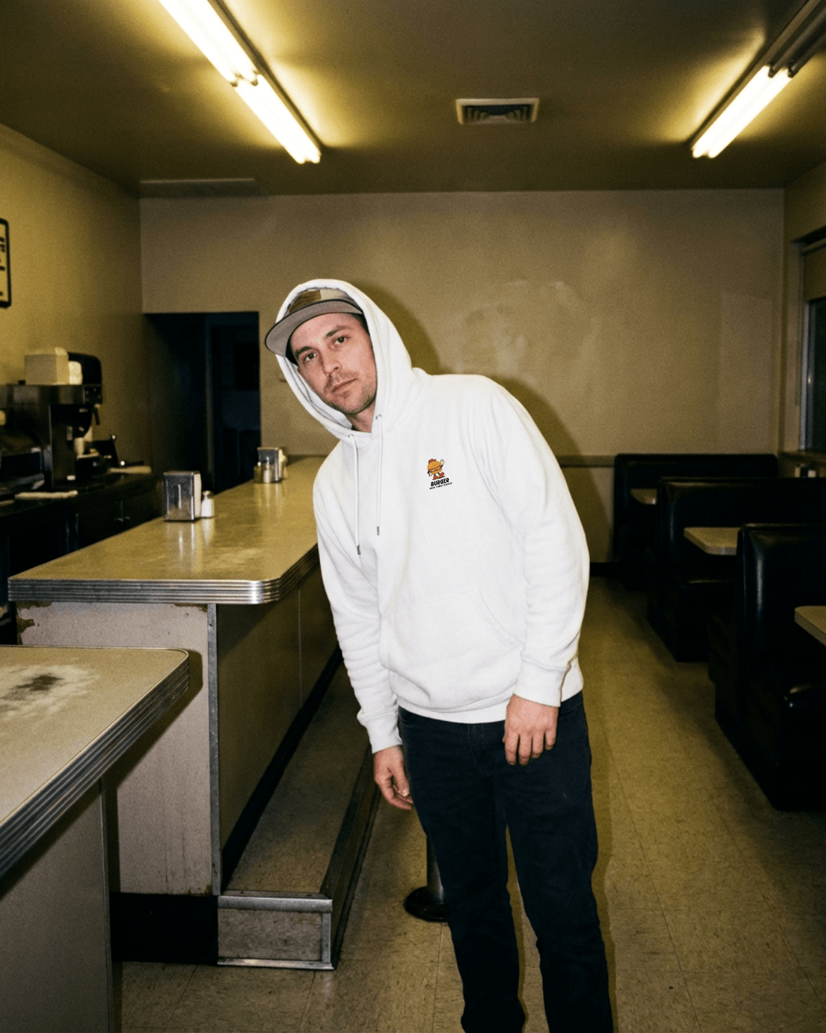 Vintage Burger Hoodie – Good Times Service (White) worn by a man in a diner setting.