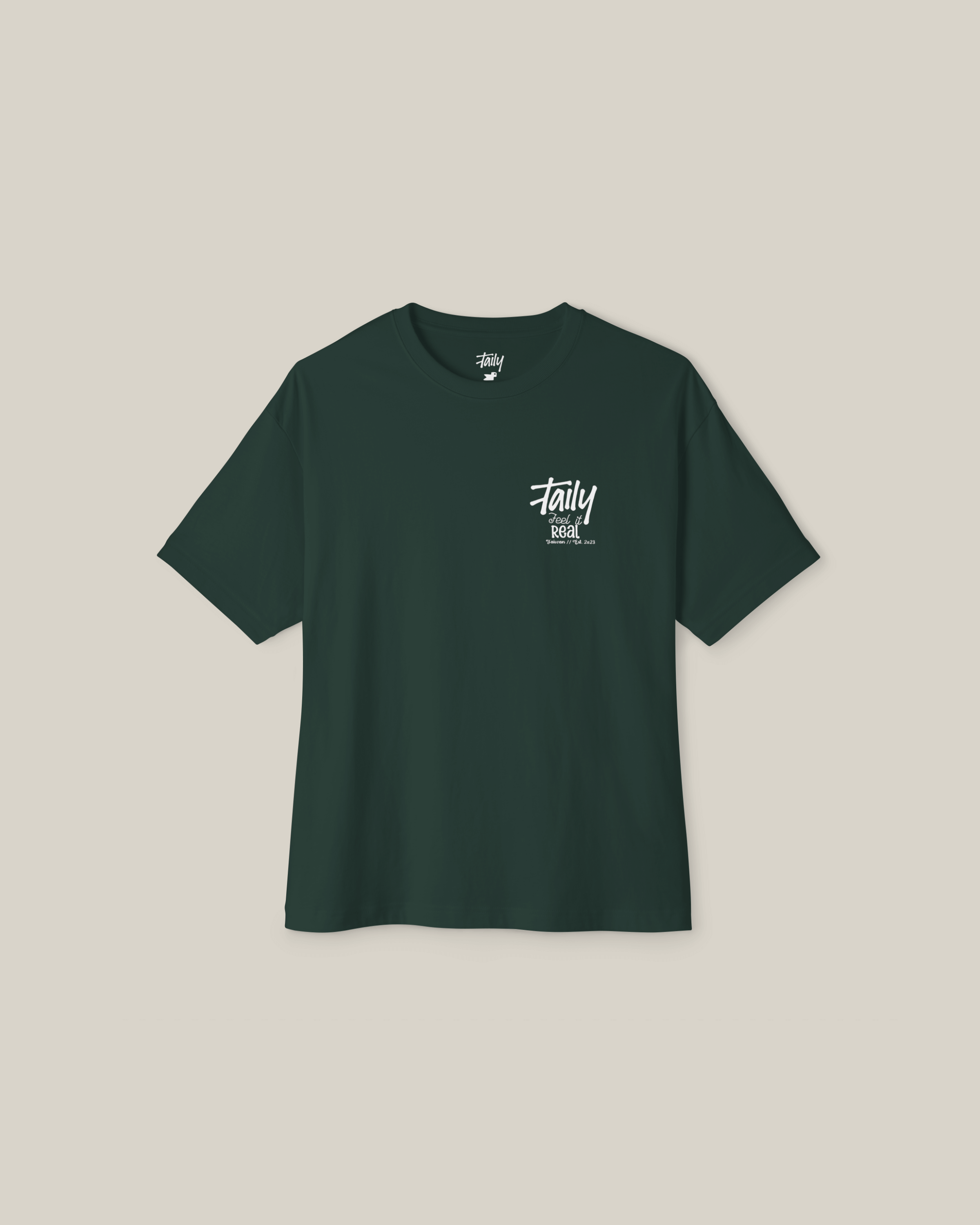 Taily Feel It Real Boxy Tee in forest green with chest logo and Feel It Real lettering on back.
