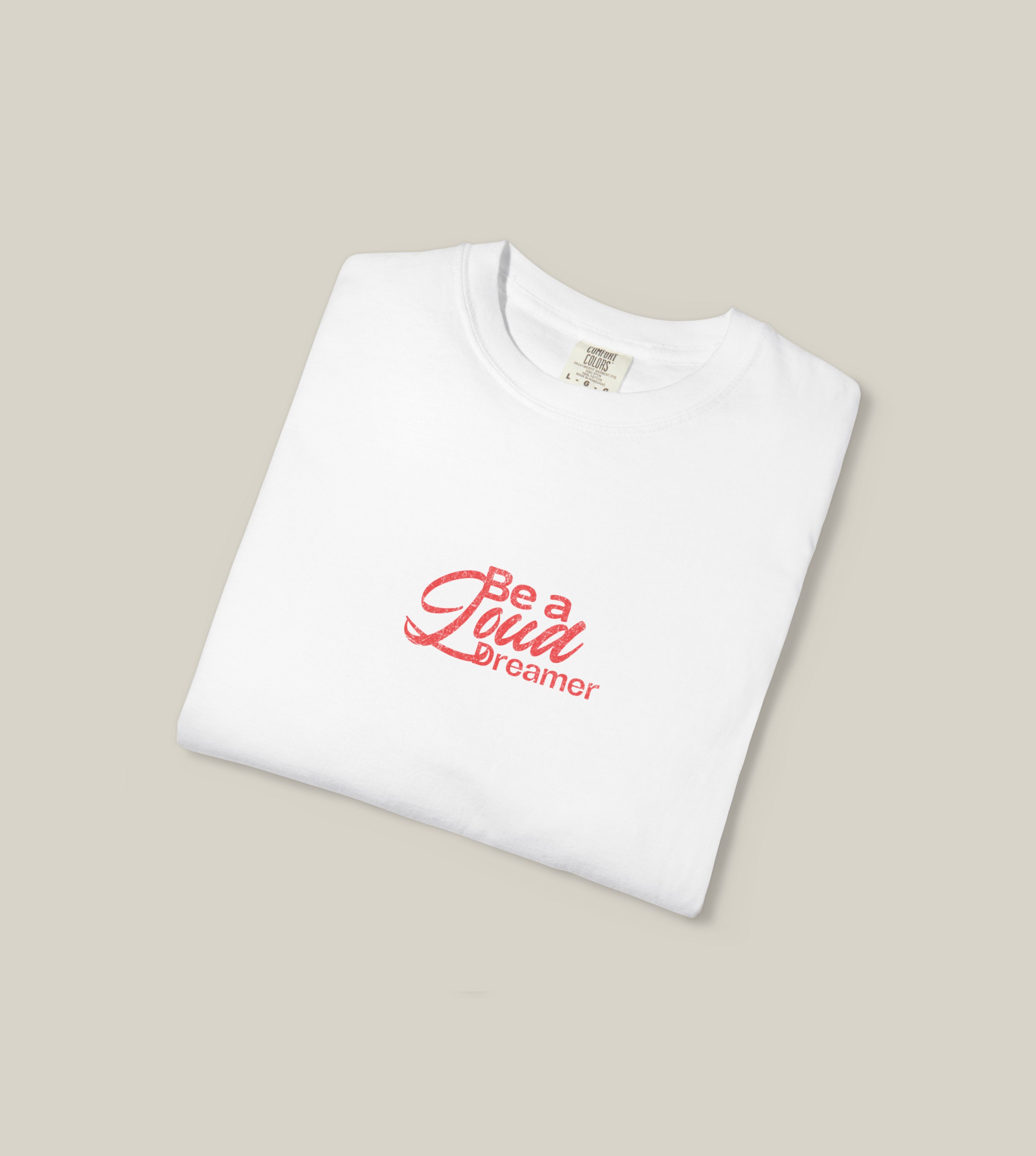 Be a Loud Dreamer Tee featuring minimal script on soft cotton, folded white t-shirt with red lettering.
