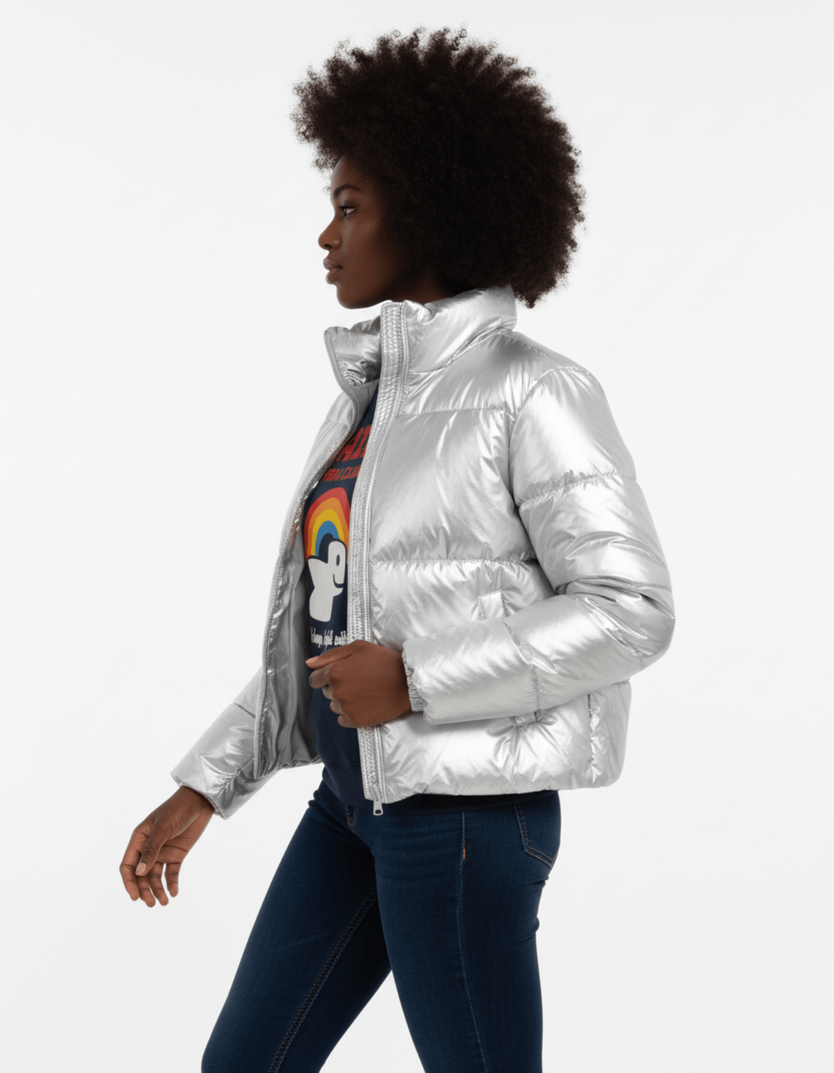 Model wearing a silver puffer jacket over a graphic tee with rainbow design, showcasing a modern winter look.