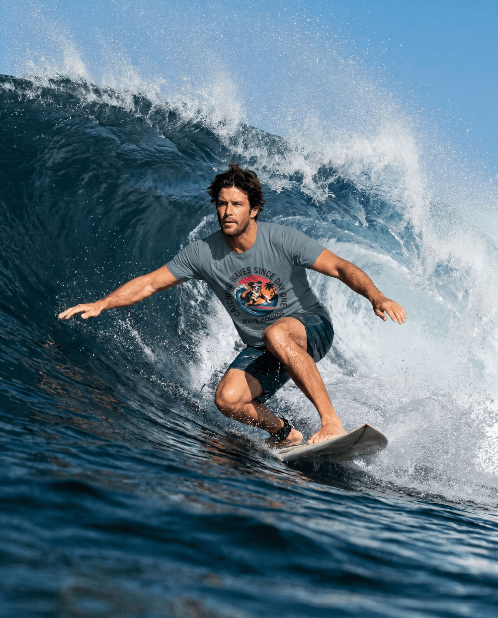 Surfer riding a wave in a Wave Hounds Surf Tee – Ice Blue, showcasing a retro surf graphic and ocean vibes.