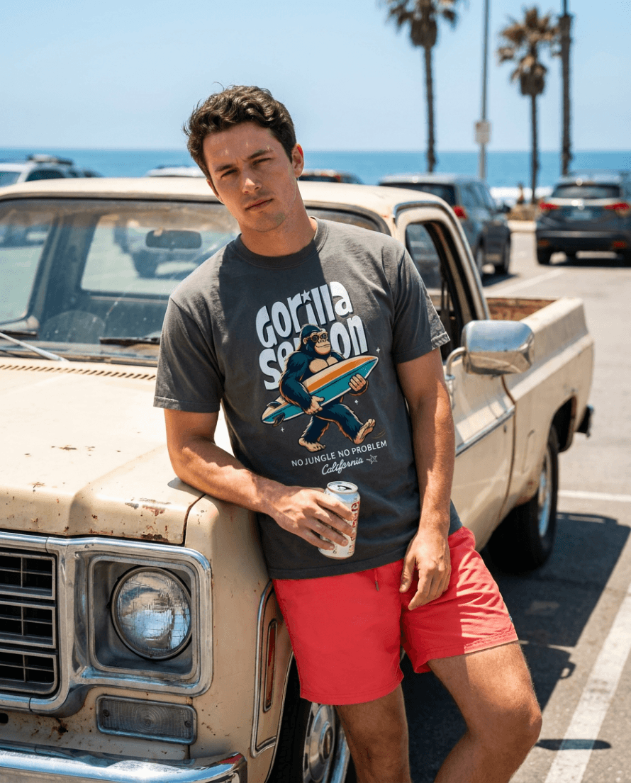 Gorilla Season Surf Tee – Pepper worn by a man with surfboard graphic, posing by a vintage truck at the beach.
