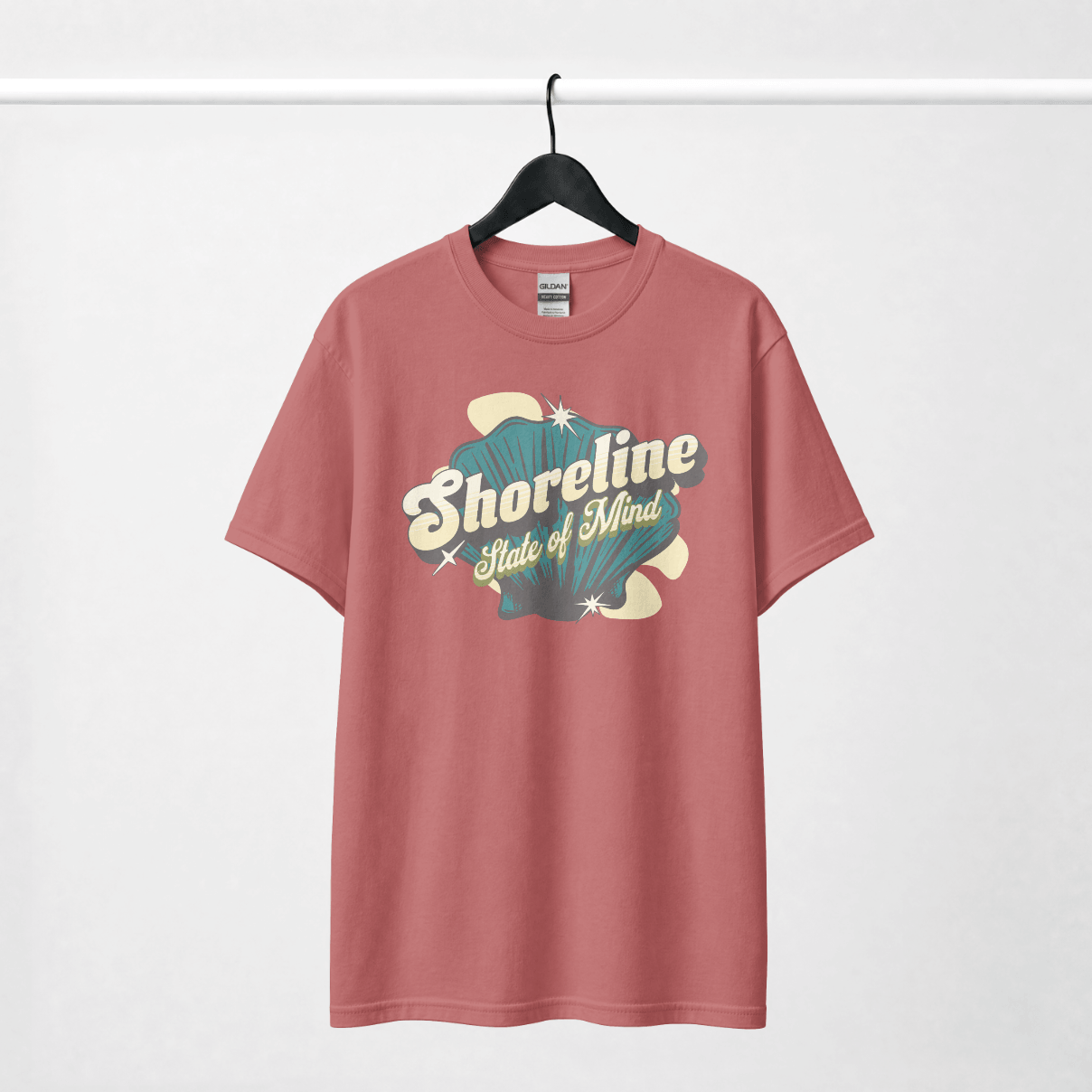 Shoreline State of Mind Tee – Crimson with seashell graphic on a hanger.