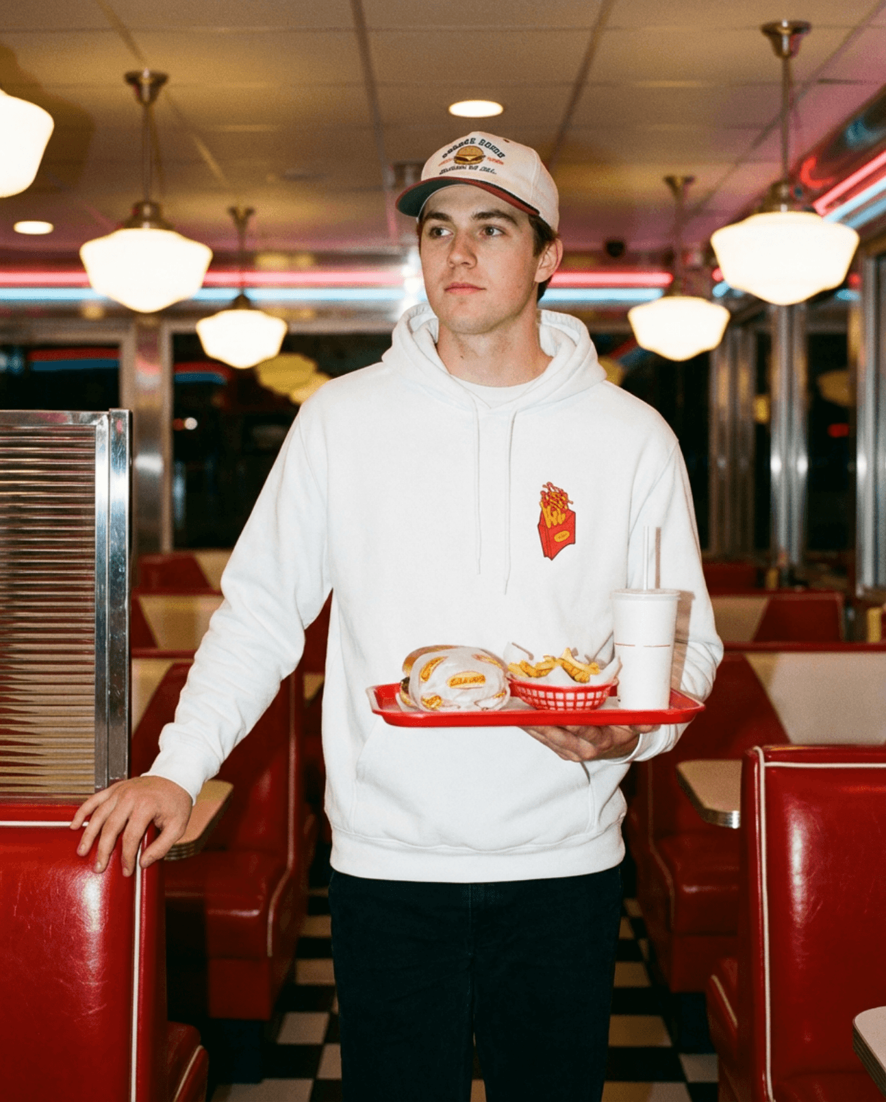 Good Fries Only Retro French Fries Hoodie – White worn by a man in a diner holding a tray with food.