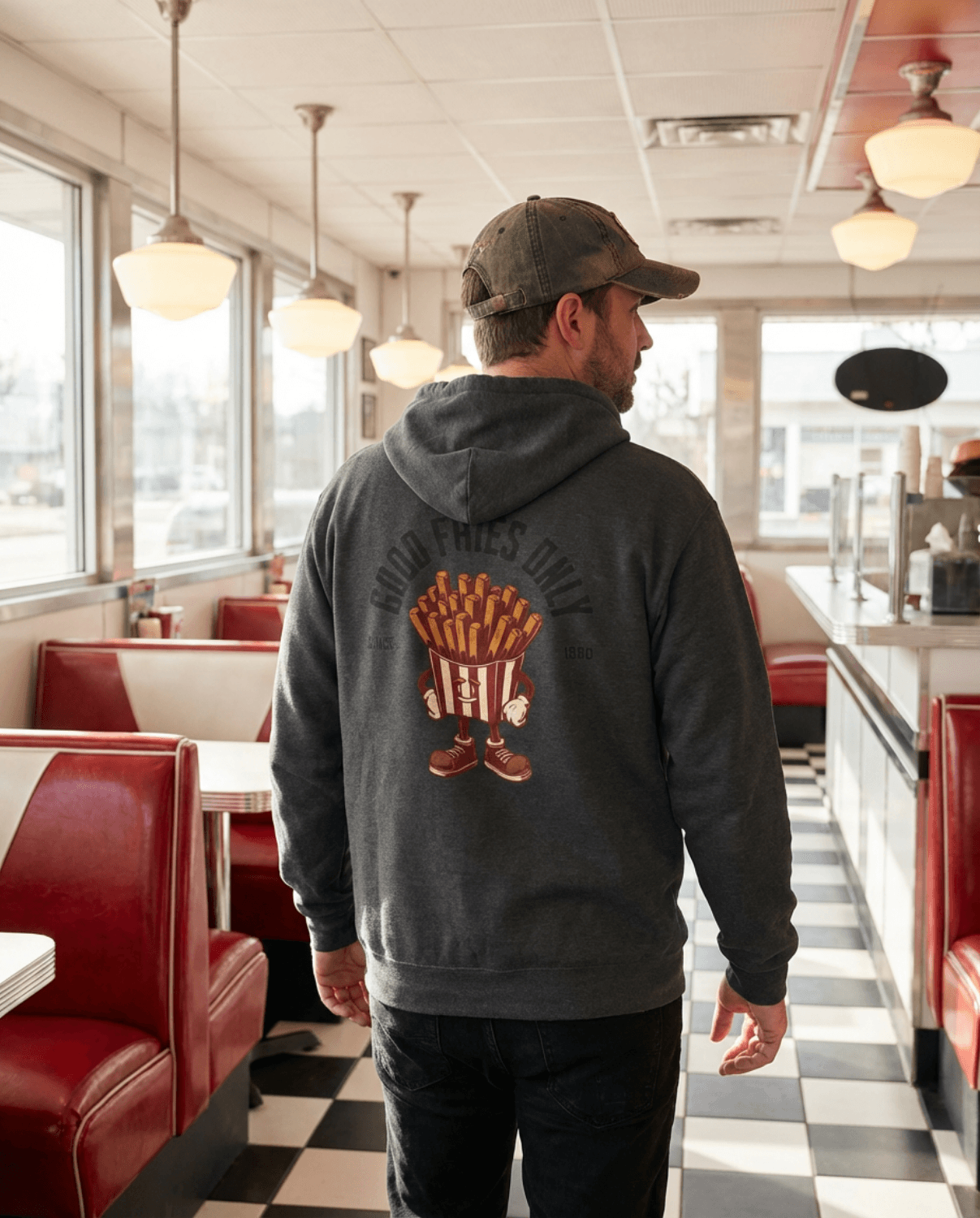 Man wearing Good Fries Only Retro French Fries Hoodie – Dark Heather in a diner.