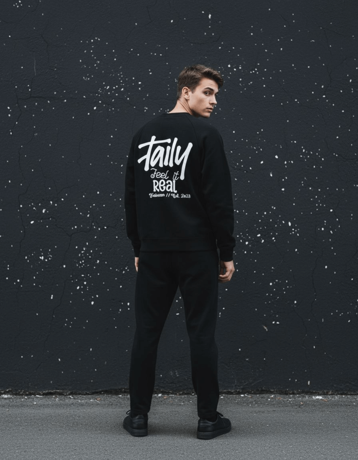 Model wearing Taily Feel It Real Sweatshirt in black, showcasing streetwear graphic sweatshirt style with bold lettering.