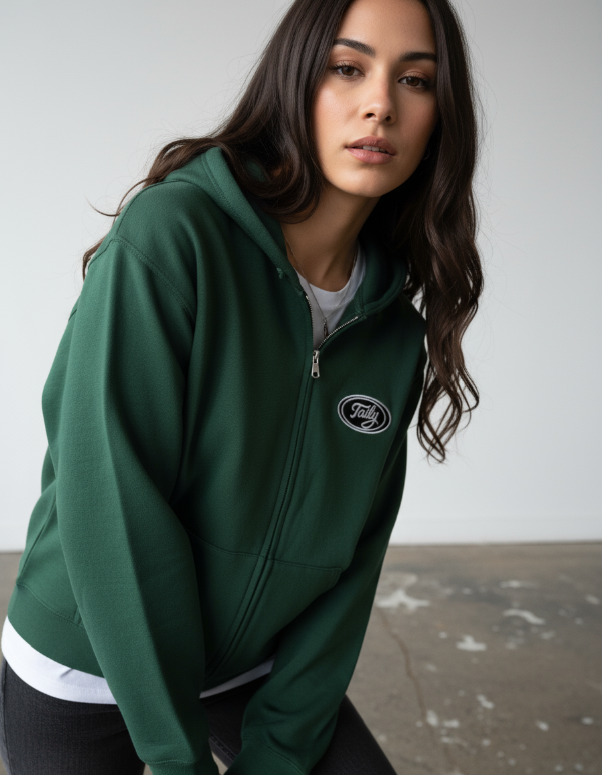 Model wearing Taily Zip Hoodie in forest green, featuring embroidered logo and relaxed fit, perfect for streetwear.