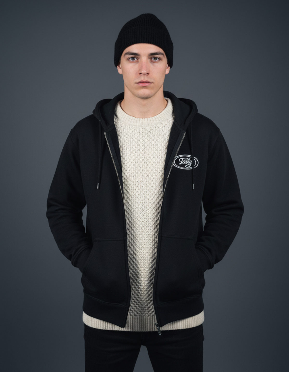 Model wearing Taily Zip Hoodie in black, styled with a knitted sweater and beanie, showcasing classic streetwear.