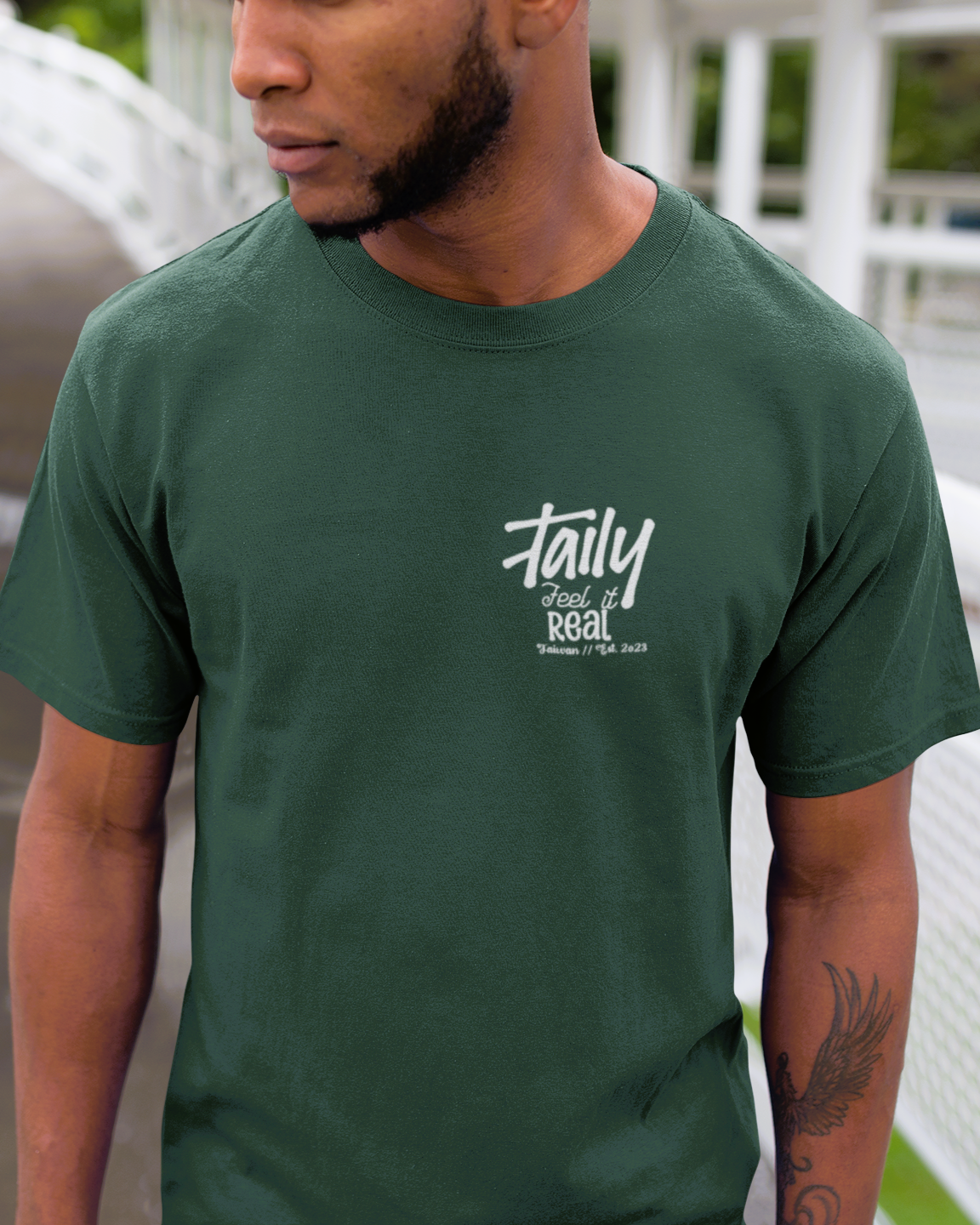 Model wearing Taily Feel It Real Boxy Tee in forest green, featuring chest logo and bold lettering.