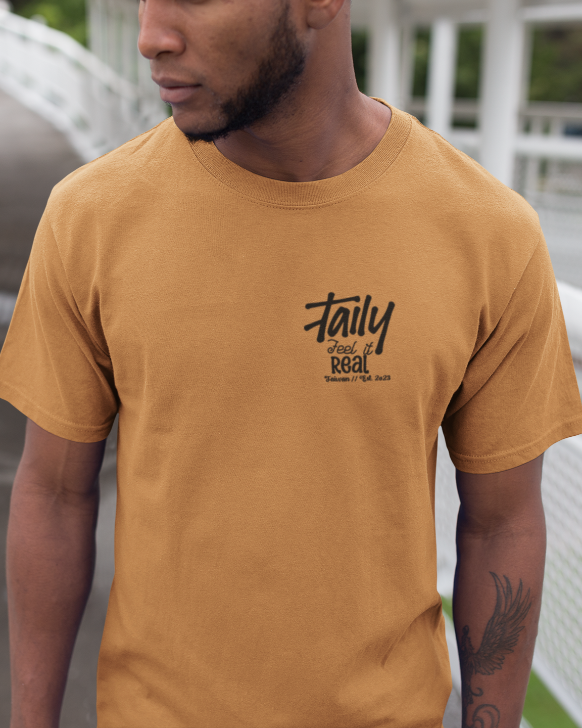 Model wearing Taily Feel It Real Boxy Tee in toast, featuring chest logo and bold lettering, ideal for streetwear style.