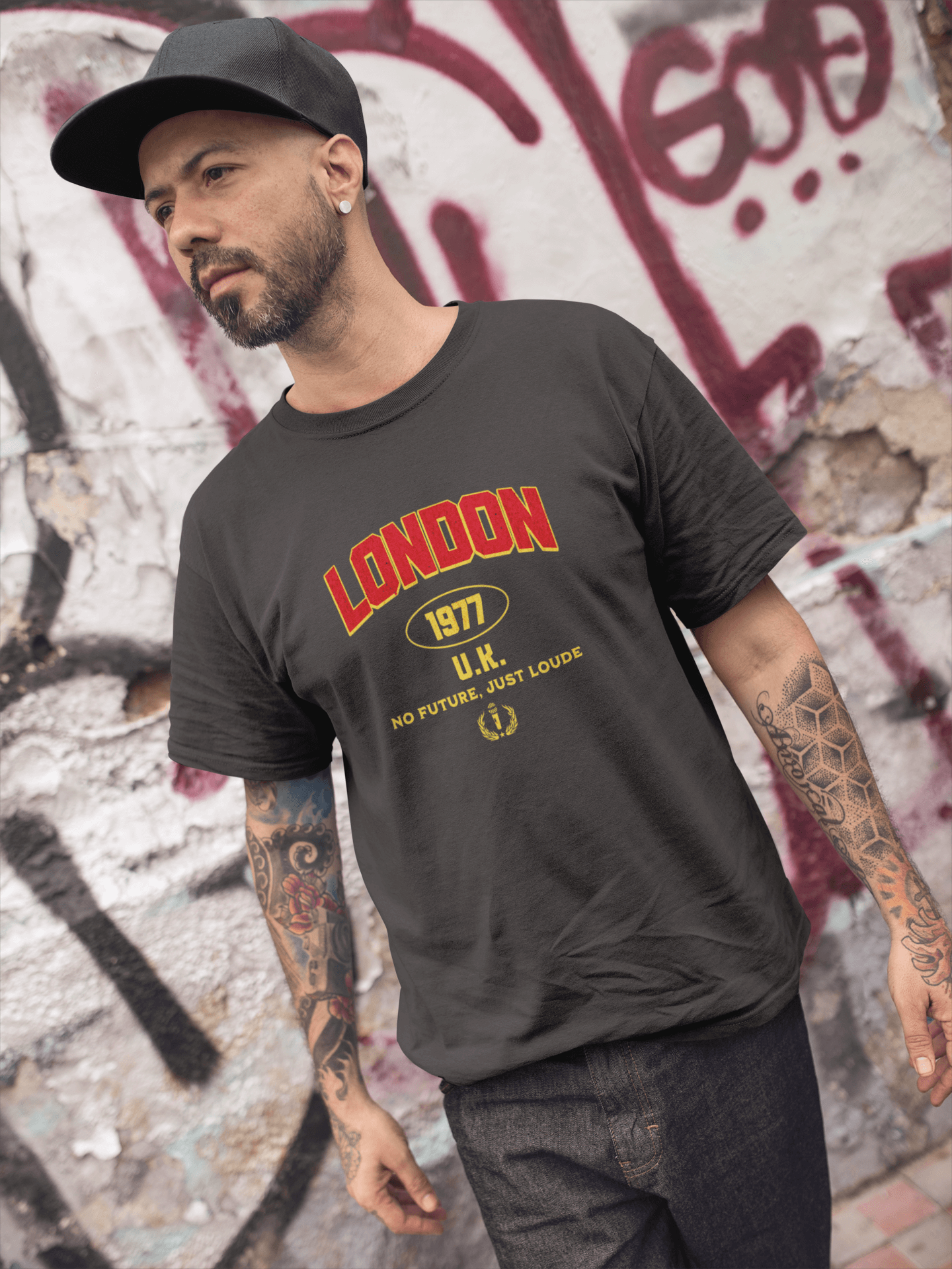 Man wearing a London 1977 unisex tee with bold lettering against a graffiti background.