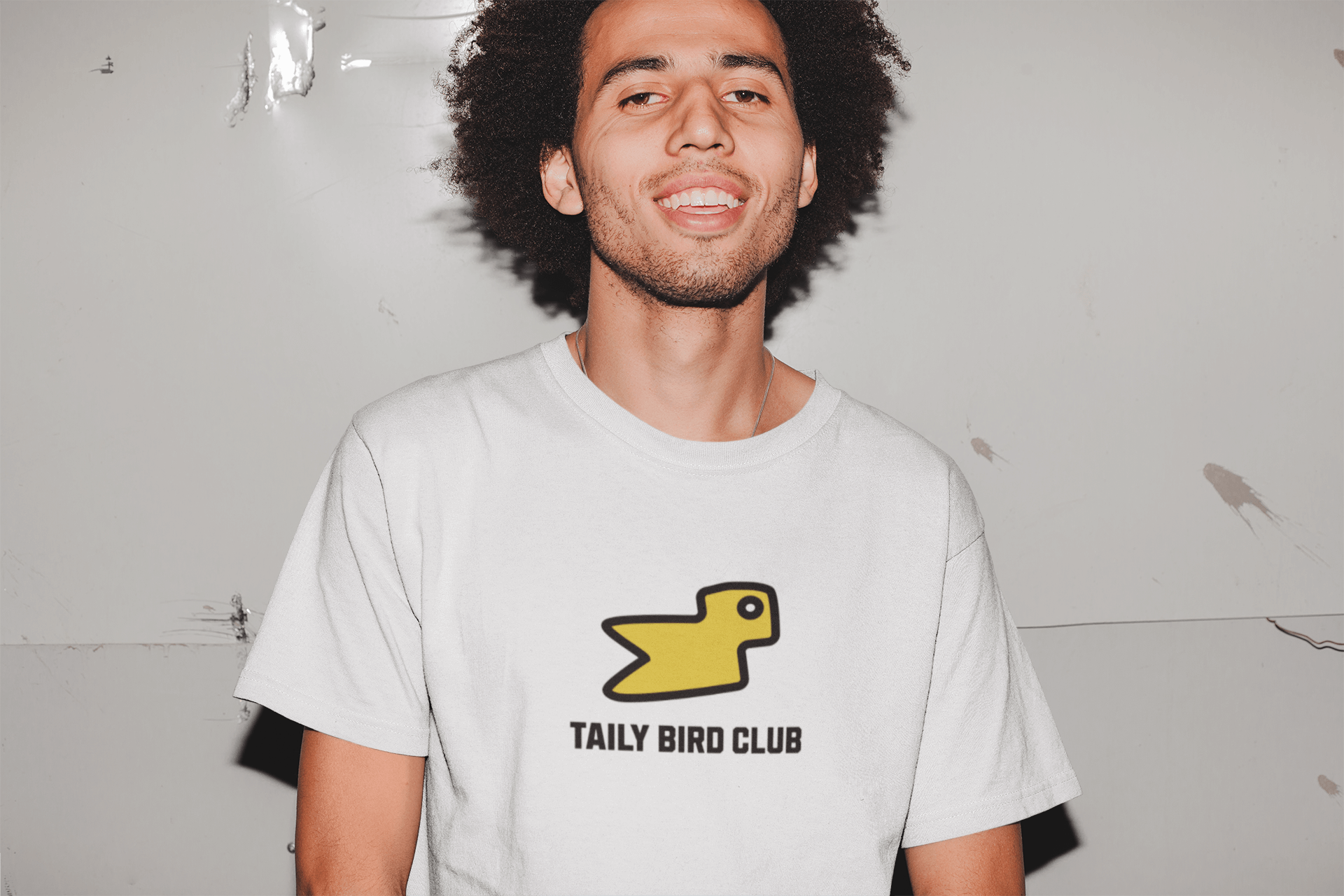 Model wearing Taily Bird Club white boxy t-shirt with yellow bird graphic, showcasing streetwear style and comfort.