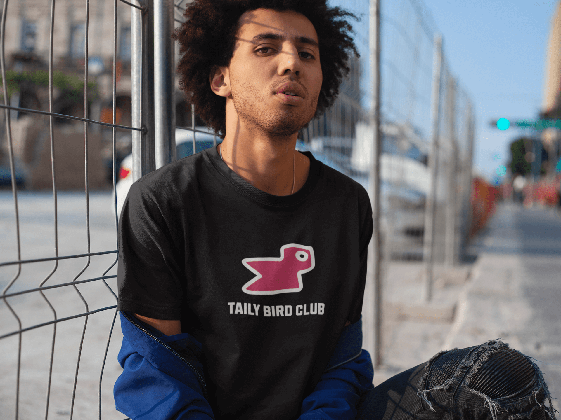 Model wearing Taily Bird Club black boxy t-shirt with pink bird print, showcasing streetwear style and modern fit.