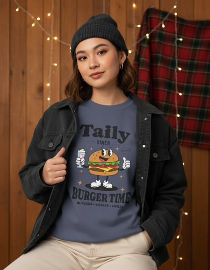 Model wearing Taily Diner Burger Time sweatshirt with burger mascot, smiles, and slogan in a cozy setting.