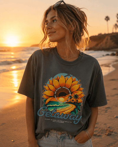 Model wearing Getaway Sunflower Beach Tee – Pepper on the beach at sunset, featuring a sunflower design.