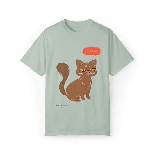 Light green T-shirt featuring a brown cat illustration with the phrase 'Life is tough!' and a humorous note '...but I'm cuter!