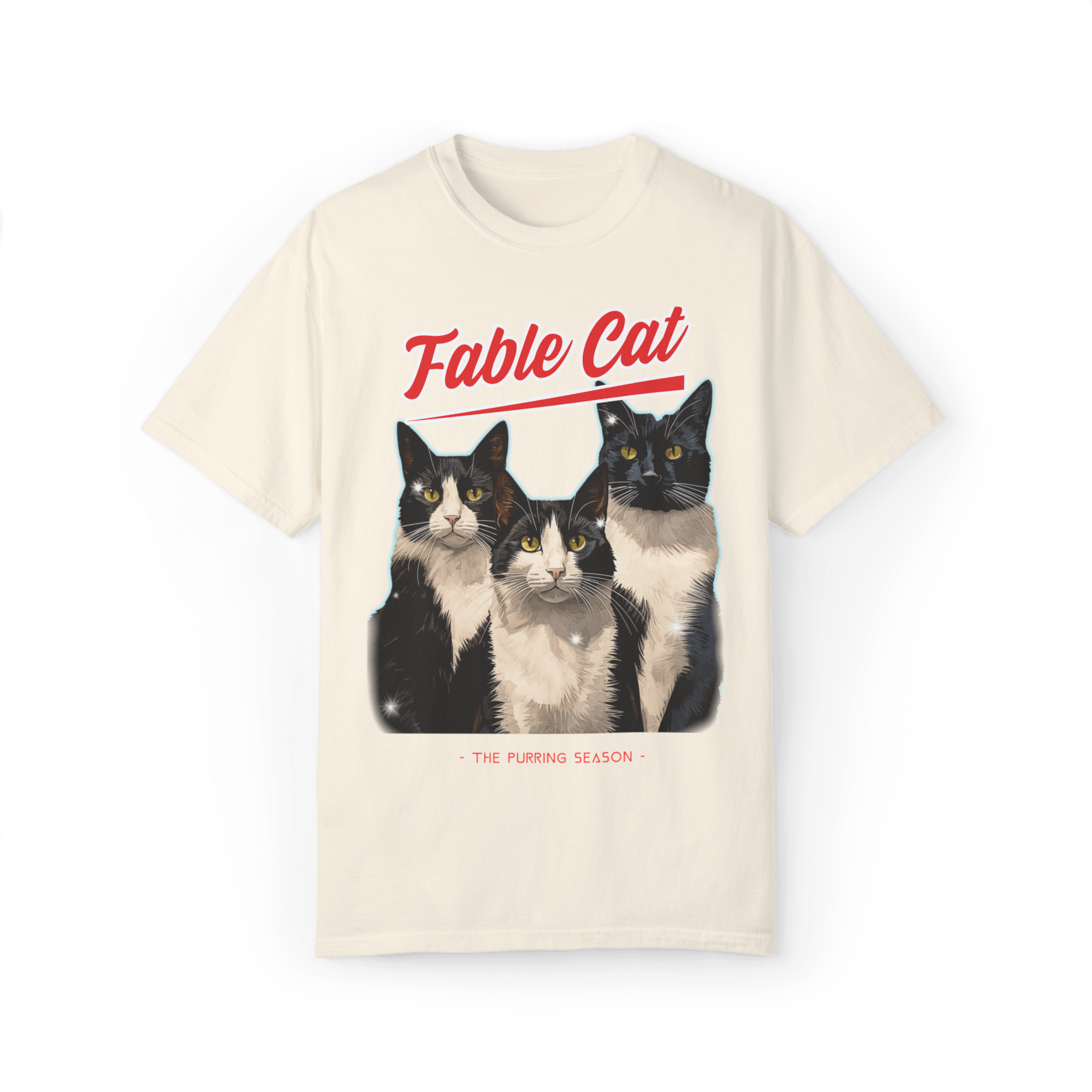 Cream-colored T-shirt featuring an illustration of three tuxedo cats, with bold red text 'Fable Cat' above and the subtitle 'The Purring Season' below.