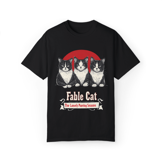 Black T-shirt featuring a 'Fable Cat' design with three black-and-white cats in front of a red circle, accompanied by the tagline 'The Lonely Purring Season.