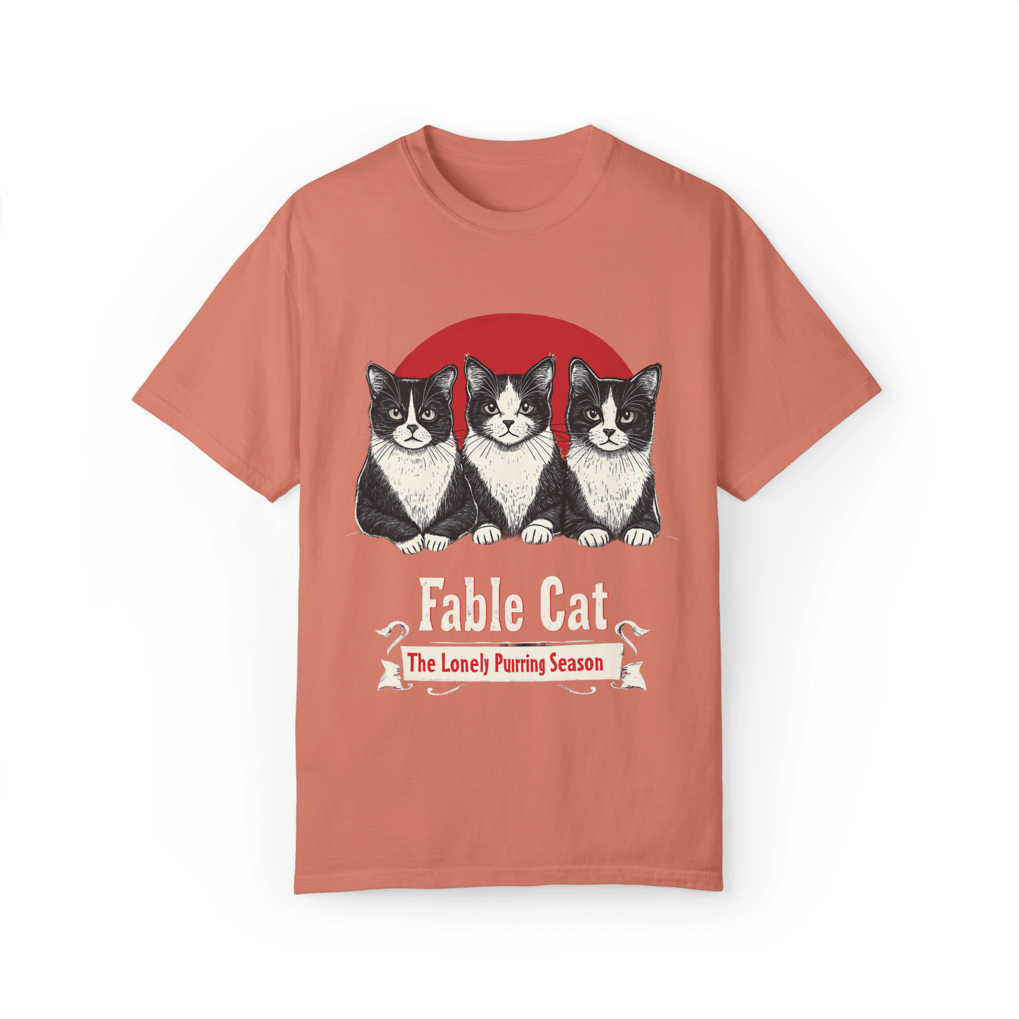 Coral pink T-shirt featuring a 'Fable Cat' design with three black-and-white cats sitting in front of a red circle, accompanied by the tagline 'The Lonely Purring Season.