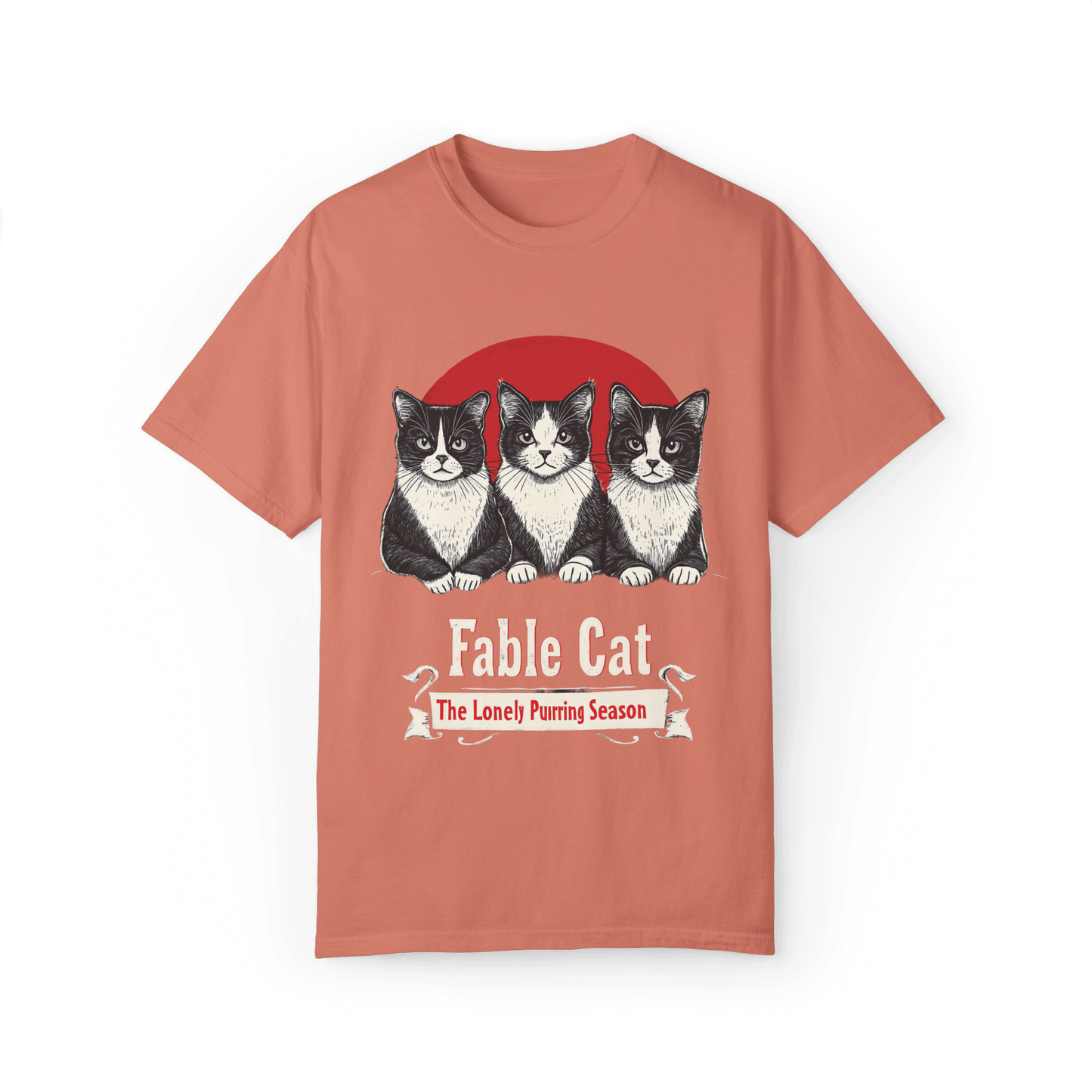 Coral pink T-shirt featuring a 'Fable Cat' design with three black-and-white cats sitting in front of a red circle, accompanied by the tagline 'The Lonely Purring Season.