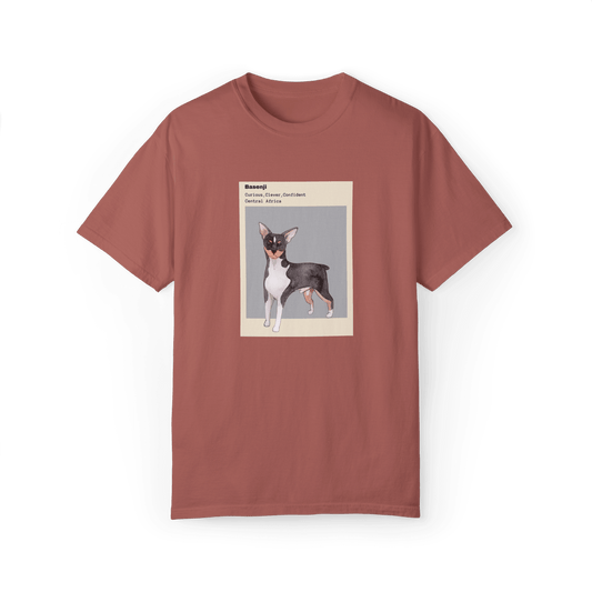 Dusty rose T-shirt featuring a watercolor illustration of a Basenji dog with text describing its traits: 'Curious, Clever, Confident,' and its origin, 'Central Africa,' framed in minimalist beige and gray design.