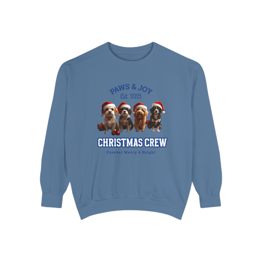 Blue Christmas-themed sweatshirt featuring the phrases "Paws & Joy Est. 2025" and "Christmas Crew," along with illustrations of four dogs wearing Santa hats, creating a joyful holiday vibe.