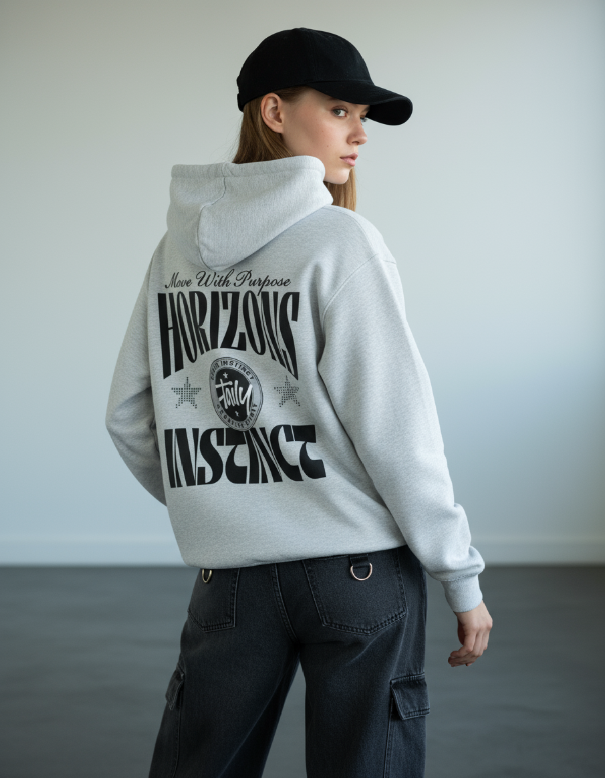 Woman wearing Taily Horizons Instinct Hoodie in Heather Grey, showcasing the unique graphic design on the back.