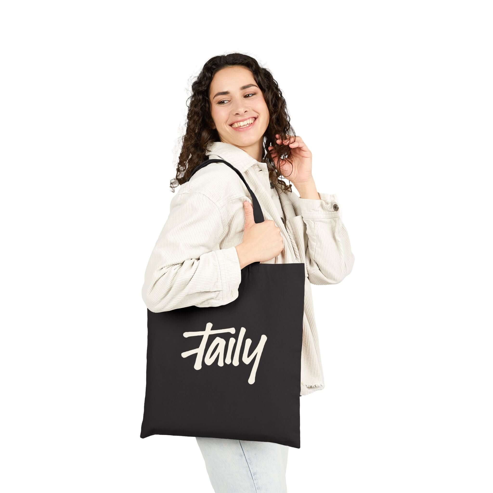 Woman holding Taily Bird Bold Canvas Tote Bag featuring logo in black and yellow, ideal for everyday use.