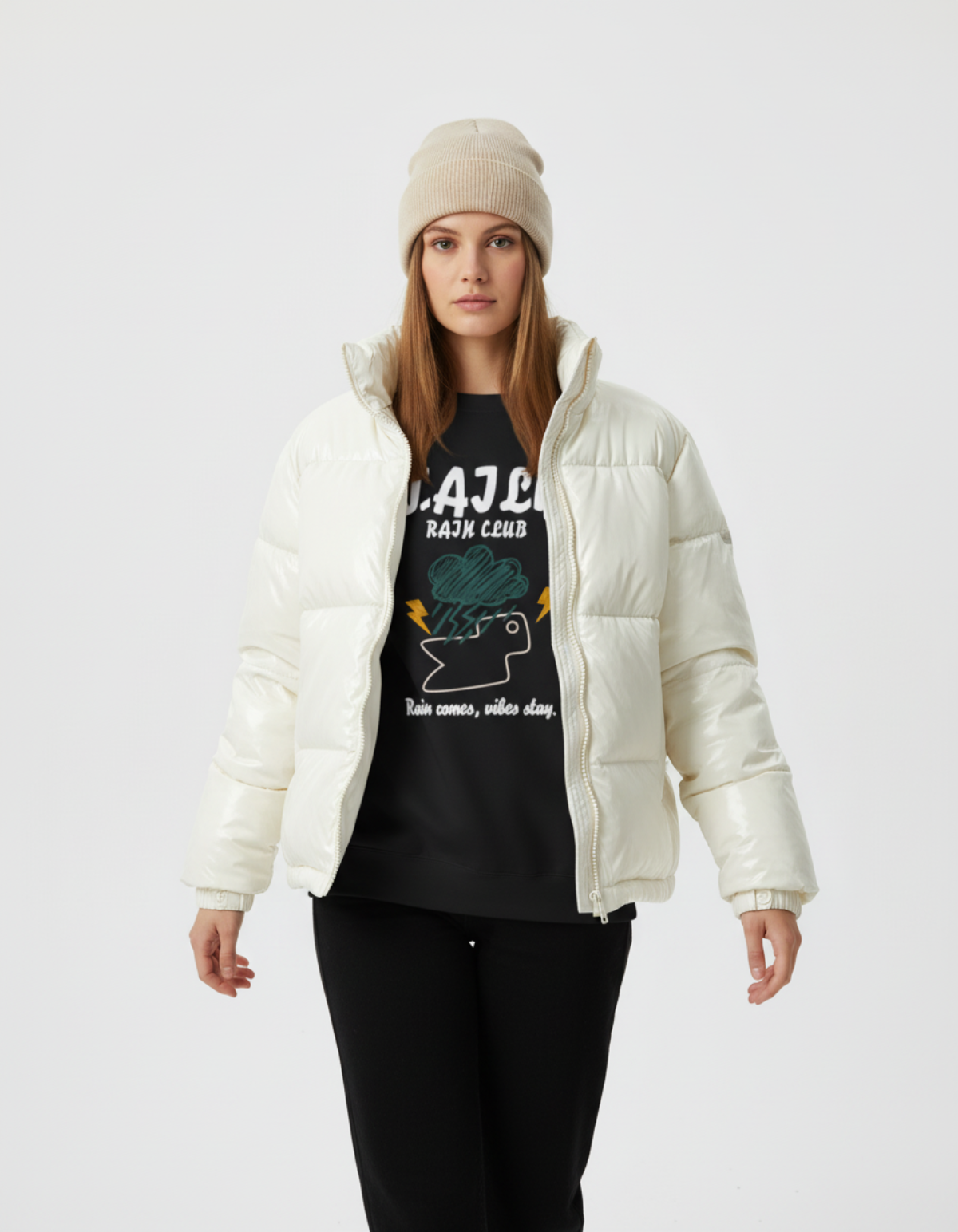 Model wearing an ivory puffer jacket over a Rain Club sweatshirt in black, featuring a bold graphic and inspirational text.