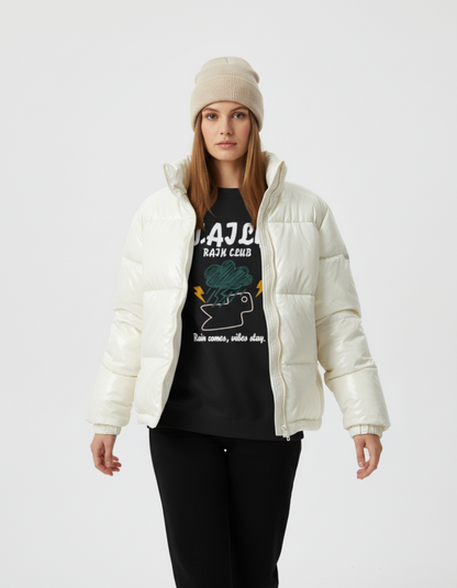 Model wearing an ivory puffer jacket over a Rain Club sweatshirt in black, featuring a bold graphic and inspirational text.