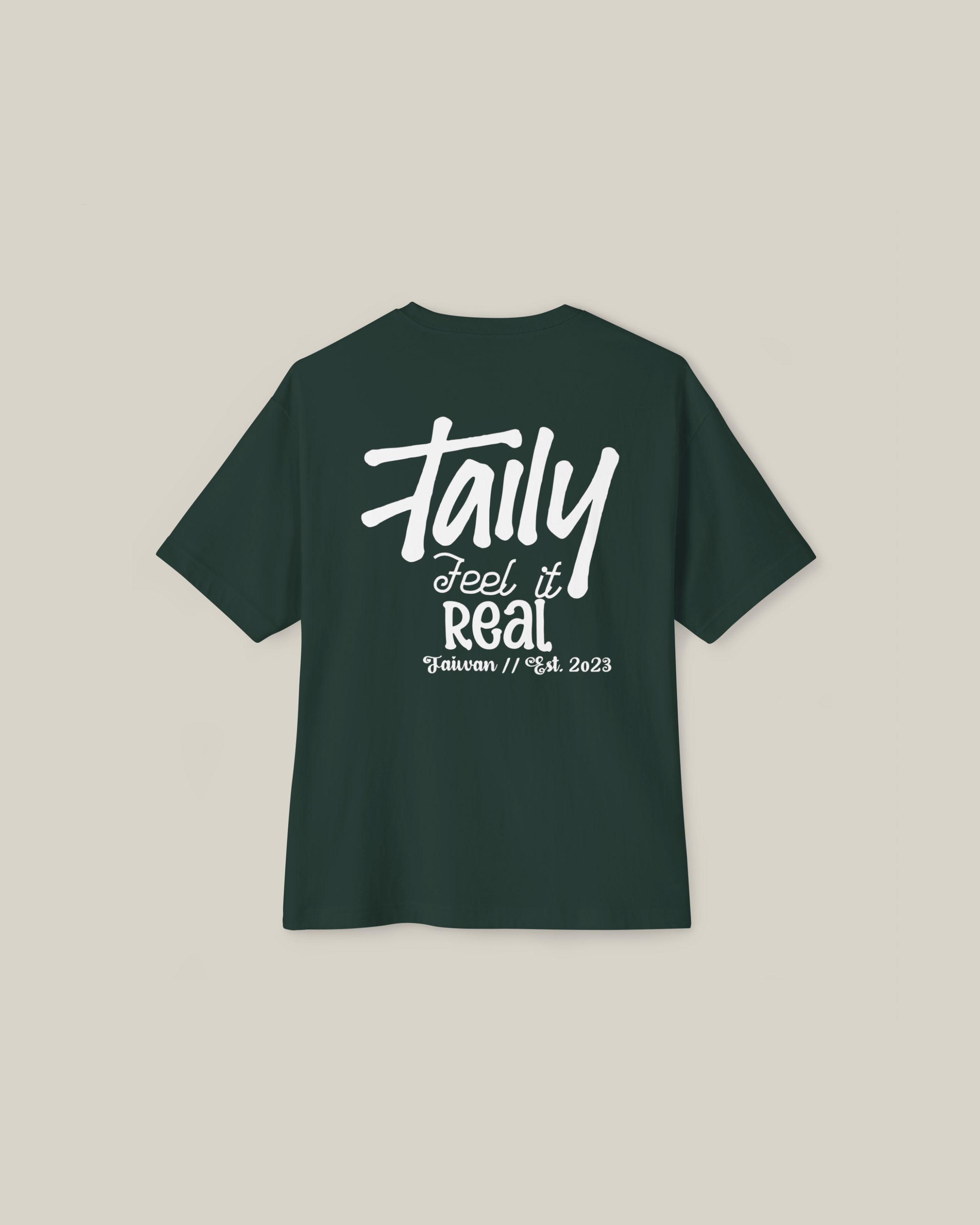 Taily Feel It Real Boxy Tee in forest green with bold lettering on the back, showcasing streetwear style.