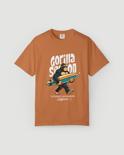 Gorilla Season Surf Tee – Yam featuring a laid-back gorilla with a surfboard on a burnt orange t-shirt.