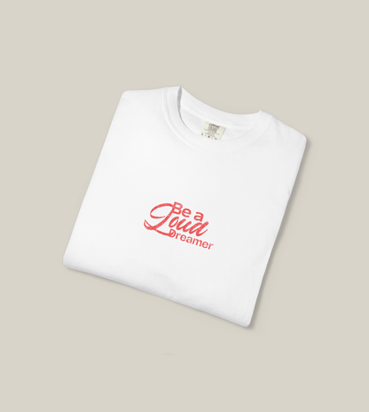 Be a Loud Dreamer Tee featuring minimal script on soft cotton, folded white t-shirt with red lettering.