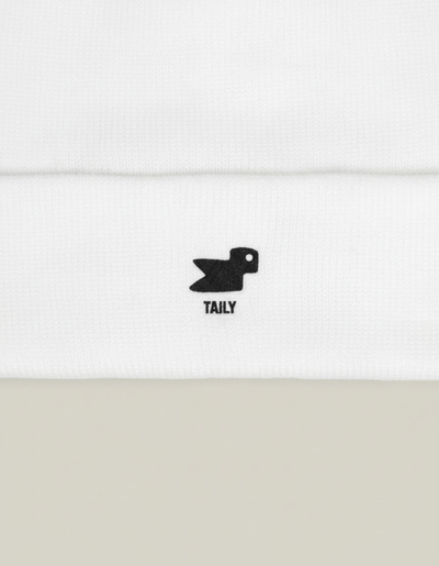 Taily Bird Knit Beanie showing minimal black embroidery on a white fabric, emphasizing comfort and streetwear style.