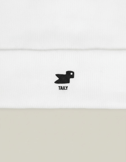 Taily Bird Knit Beanie showing minimal black embroidery on a white fabric, emphasizing comfort and streetwear style.
