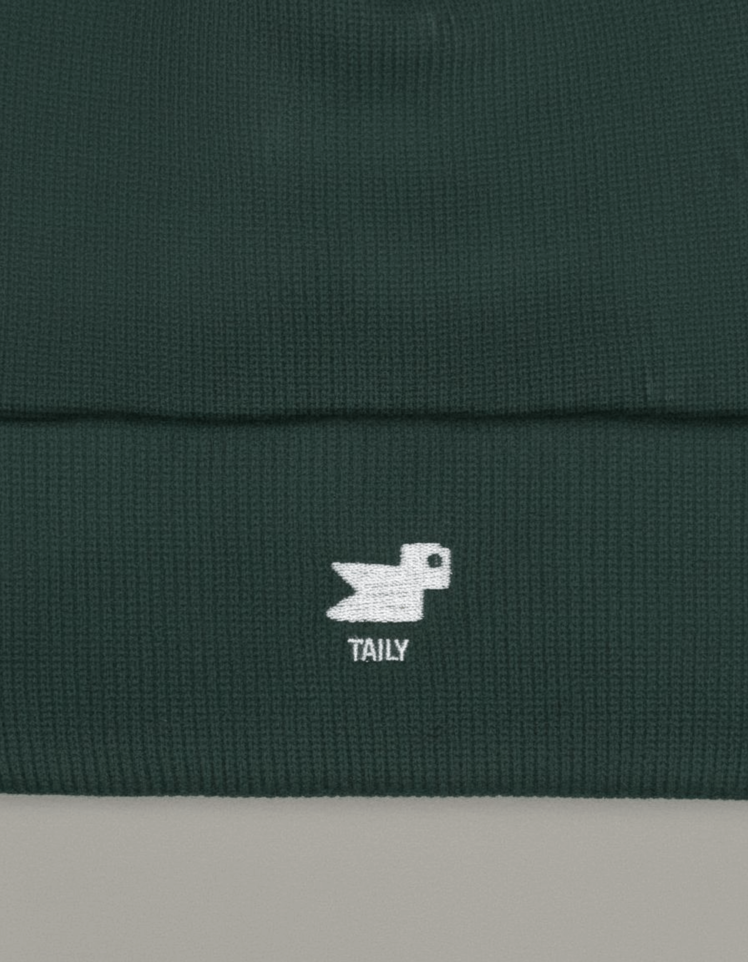 Taily Bird Knit Beanie in dark green showing minimal embroidery and comfortable fabric.