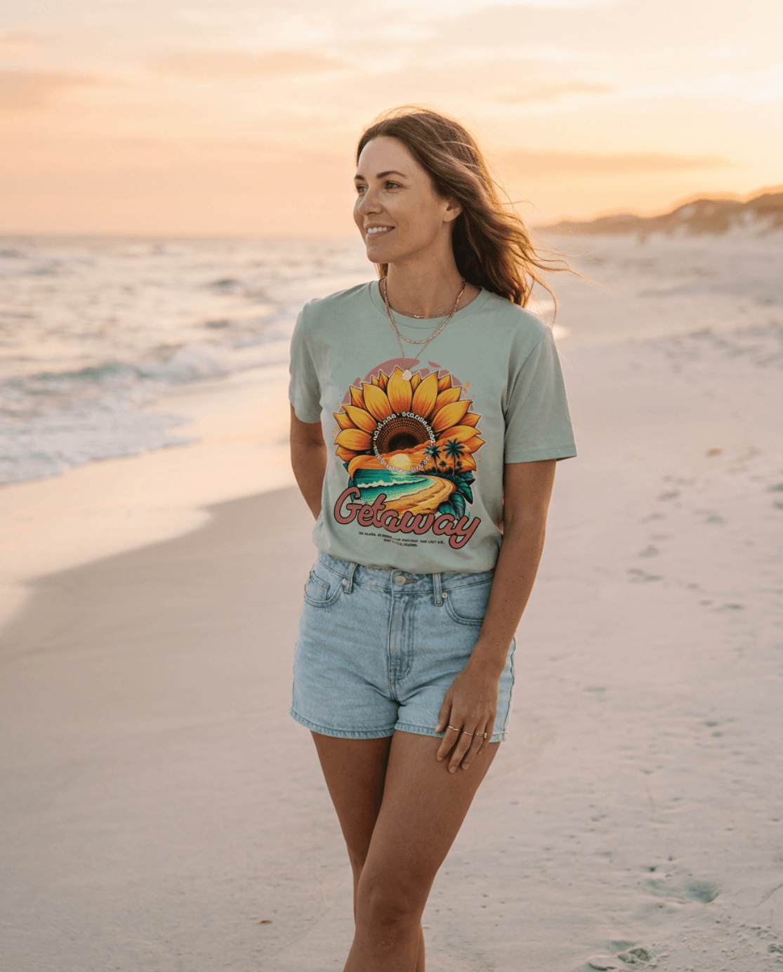 Getaway Sunflower Beach Tee – Bay worn by a woman on the beach at sunset, showcasing a vibrant sunflower design.