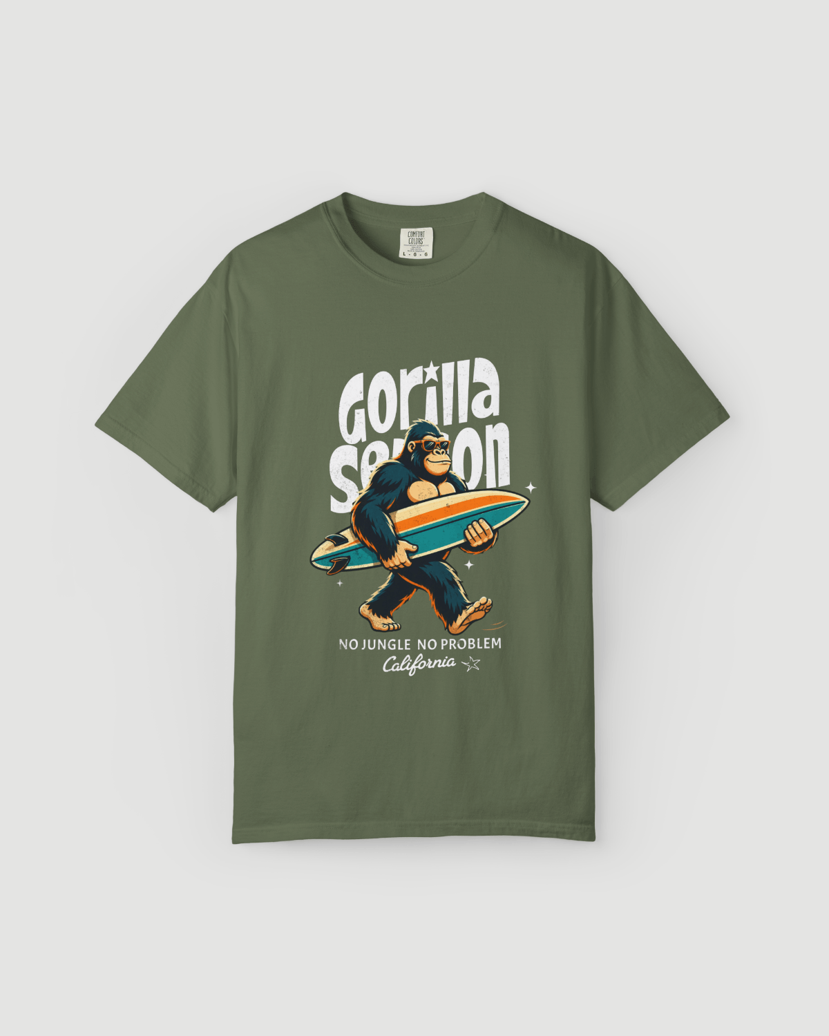 Gorilla Season Surf Tee – Sage featuring a cool gorilla with a surfboard graphic on an earthy green shirt.