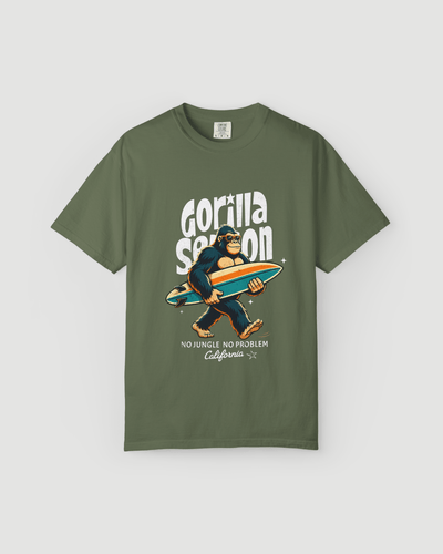 Gorilla Season Surf Tee – Sage featuring a cool gorilla with a surfboard graphic on an earthy green shirt.
