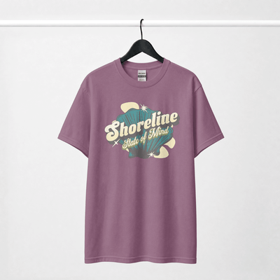 Shoreline State of Mind Tee – Berry hanging on a rack, featuring a vintage-inspired seashell graphic in teal and cream.