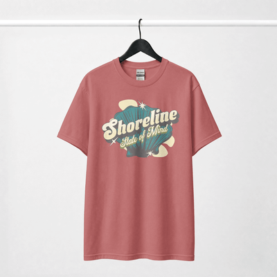 Shoreline State of Mind Tee – Crimson with seashell graphic on a hanger.