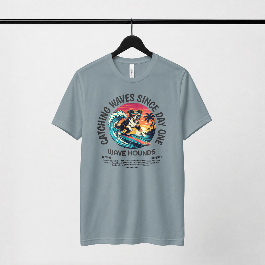 Wave Hounds Surf Tee – Ice Blue displayed on hanger with vibrant surf graphic and retro styling.