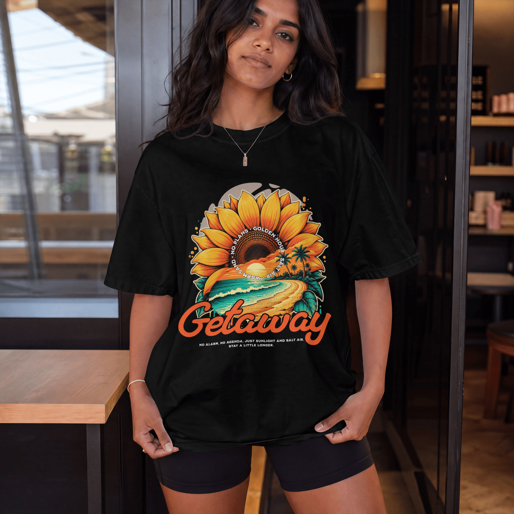 Getaway Sunflower Beach Tee – Black displayed on a model, featuring a bold sunflower and coastal road design.