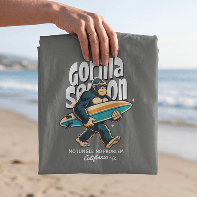 Gorilla Season Surf Tee – Pepper with laid-back gorilla graphic on a beach background.