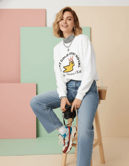 Female model wearing Taily Bird Stay Cold Stay Royal Streetwear Graphic Sweatshirt in white, posing with a camera and casual style.