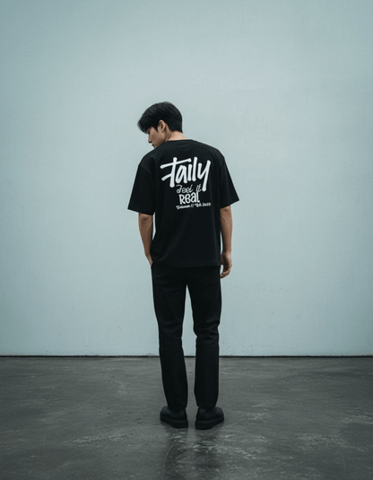 Model wearing Taily Feel It Real Boxy Tee – Black, a stylish streetwear boxy t-shirt with bold lettering.